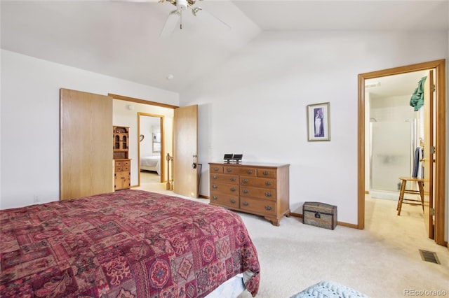 carpeted bedroom featuring ceiling fan, vaulted ceiling, and ensuite bath