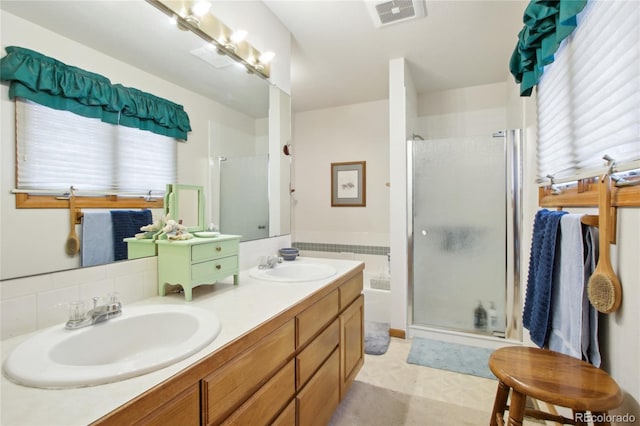 bathroom featuring tasteful backsplash, a shower with door, a healthy amount of sunlight, and vanity