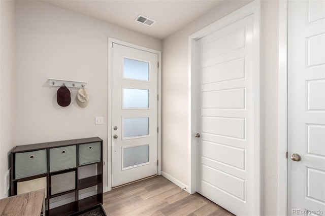 doorway to outside with light wood finished floors, visible vents, and baseboards