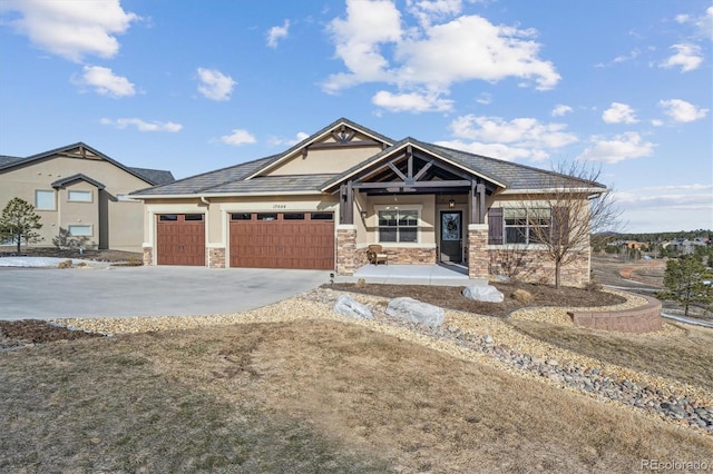 view of front of home with a garage, stone siding, driveway, and stucco siding