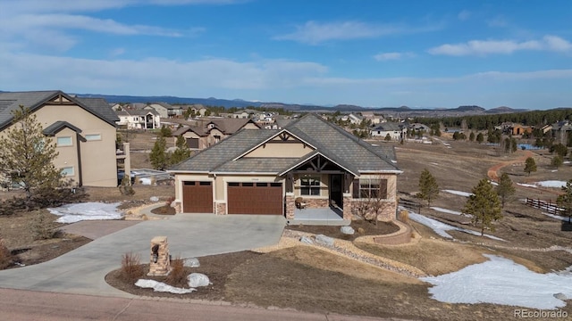 view of front facade with concrete driveway, stone siding, and a residential view