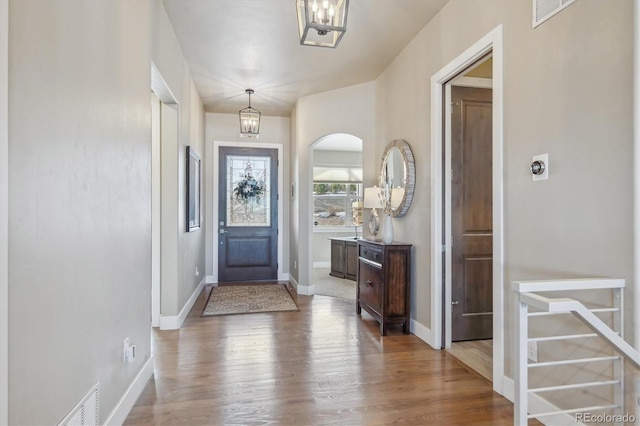 foyer entrance featuring a notable chandelier, baseboards, and wood finished floors