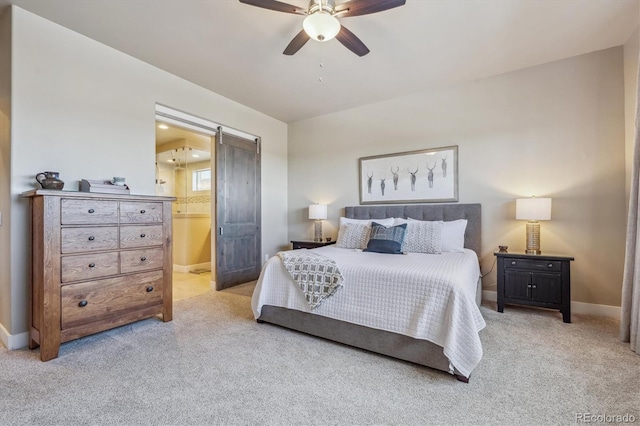 bedroom with connected bathroom, baseboards, a barn door, carpet floors, and a ceiling fan