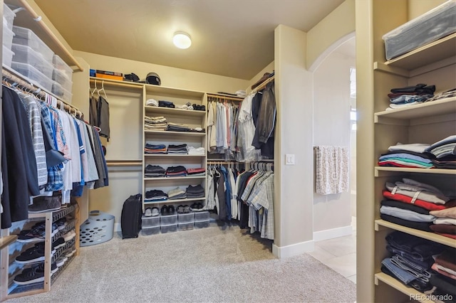 spacious closet with arched walkways, carpet, and tile patterned flooring