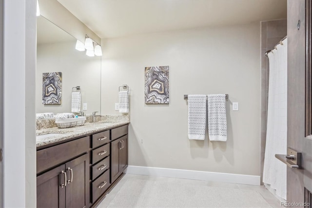 bathroom with a sink, baseboards, double vanity, and tile patterned floors