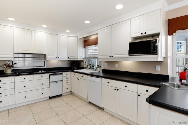 kitchen featuring dark countertops, white dishwasher, a sink, and white cabinets