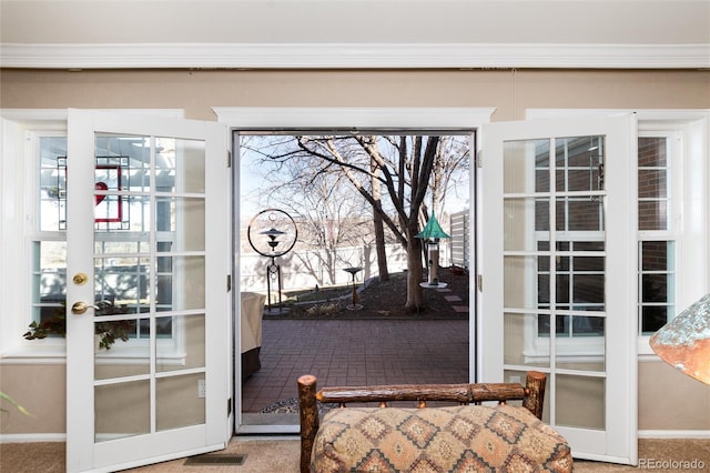 doorway with ornamental molding, a healthy amount of sunlight, visible vents, and brick floor