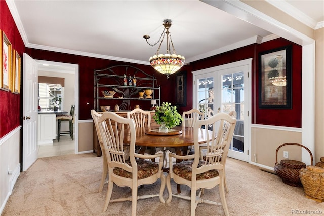 dining room with french doors, crown molding, and light colored carpet