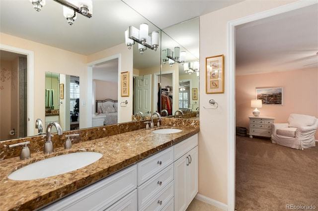 ensuite bathroom featuring ensuite bathroom, double vanity, a sink, and baseboards