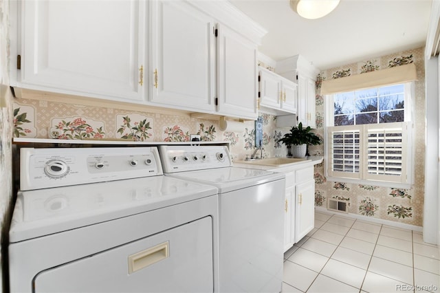 clothes washing area with washing machine and clothes dryer, visible vents, cabinet space, a sink, and wallpapered walls