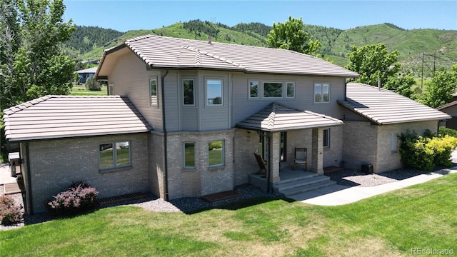 10886 Pheasant Run, Littleton, CO 80125 - rear view of property with a mountain view, brick siding, a yard, and a tiled roof