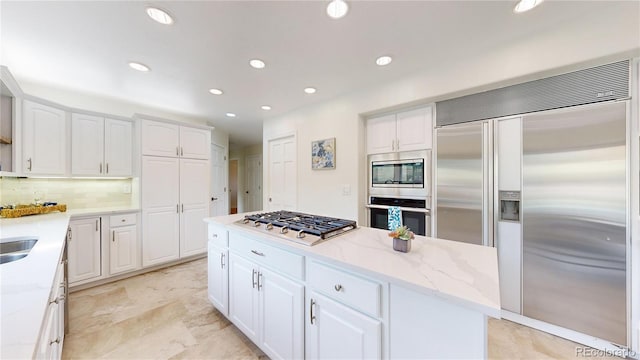 10886 Pheasant Run, Littleton, CO 80125 - kitchen featuring built in appliances, decorative backsplash, a kitchen island, white cabinets, and recessed lighting