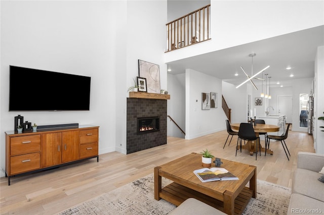 living room with baseboards, light wood-style floors, a chandelier, and a fireplace