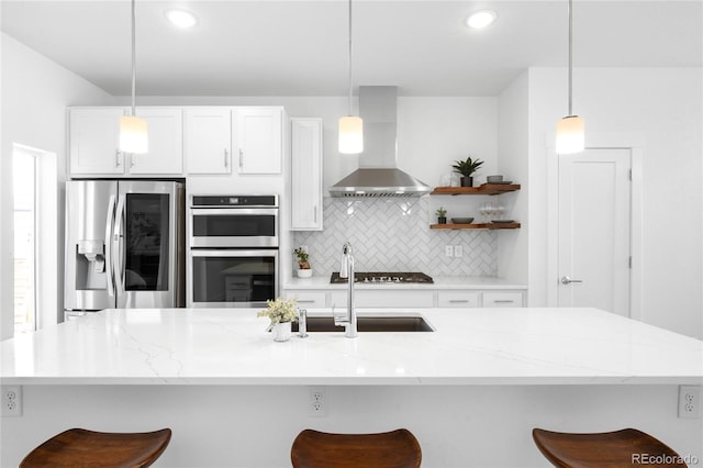 kitchen with backsplash, wall chimney range hood, decorative light fixtures, a kitchen breakfast bar, and stainless steel appliances