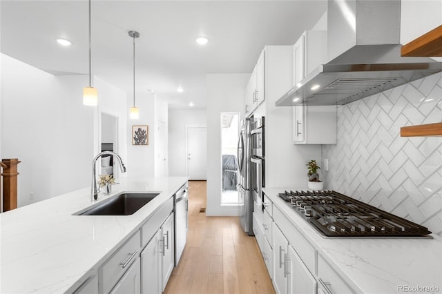 kitchen with a sink, white cabinetry, stainless steel appliances, wall chimney exhaust hood, and decorative backsplash