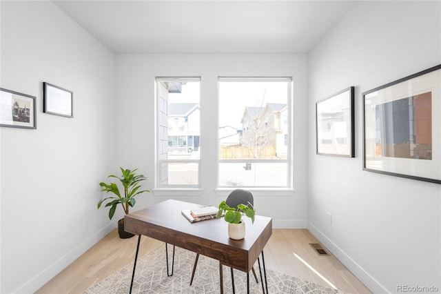 office with baseboards, visible vents, and light wood finished floors