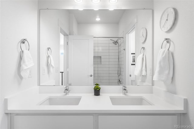 bathroom with a sink, double vanity, and a tile shower