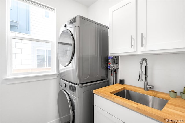 laundry room with a sink, cabinet space, and stacked washing maching and dryer