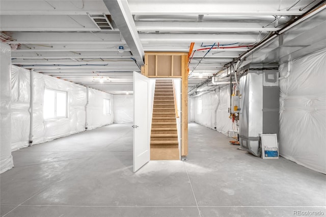 basement with gas water heater, stairway, heating unit, and visible vents