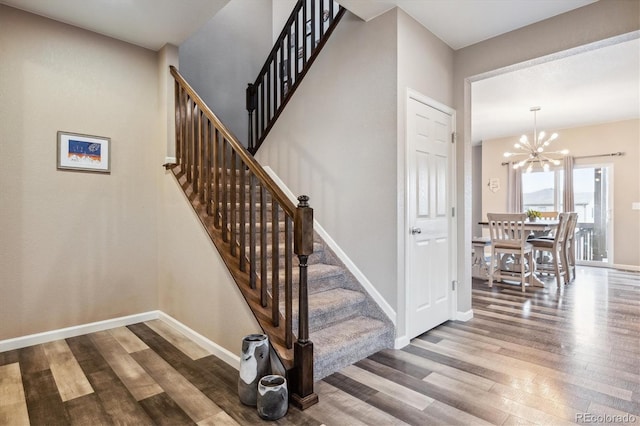 stairs with an inviting chandelier and hardwood / wood-style flooring