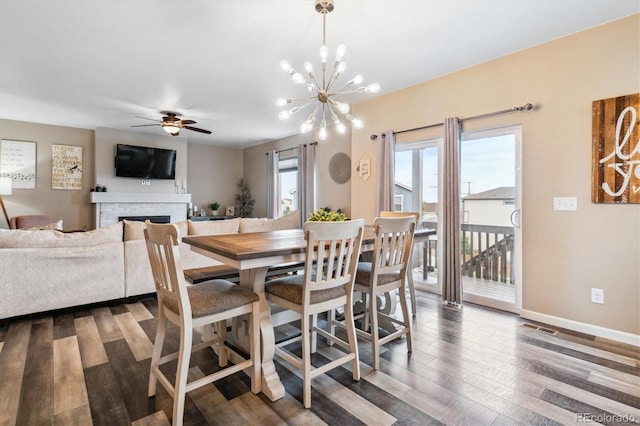 dining area featuring ceiling fan with notable chandelier and dark wood-type flooring