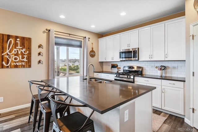 kitchen with stainless steel appliances, a center island with sink, white cabinetry, and sink