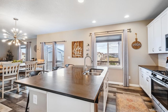 kitchen with a kitchen island with sink, hardwood / wood-style floors, sink, appliances with stainless steel finishes, and white cabinets