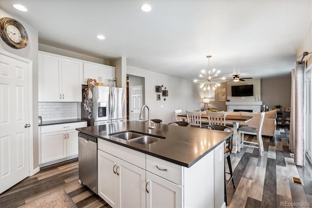 kitchen with appliances with stainless steel finishes, sink, white cabinets, and a center island with sink