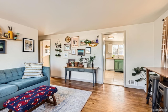 living room featuring sink and light hardwood / wood-style flooring