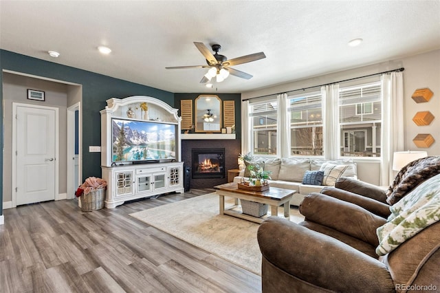 599 Fall River Ct, Brighton, CO 80601 - living area featuring a ceiling fan, a glass covered fireplace, wood finished floors, and recessed lighting