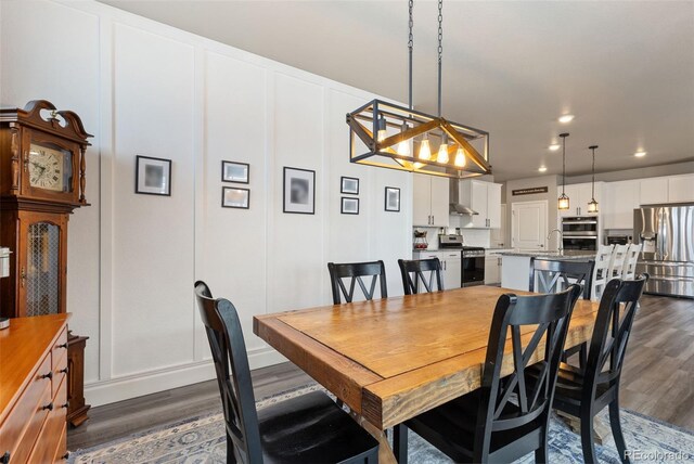 599 Fall River Ct, Brighton, CO 80601 - dining room featuring dark wood finished floors, a decorative wall, recessed lighting, and a chandelier
