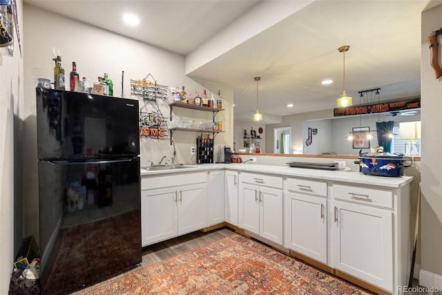 599 Fall River Ct, Brighton, CO 80601 - kitchen with freestanding refrigerator, a peninsula, light wood-style flooring, hanging light fixtures, and recessed lighting