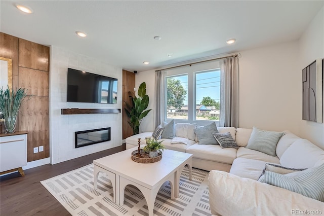 living area featuring a large fireplace, dark wood-style flooring, and recessed lighting