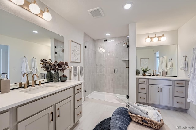 full bathroom with a stall shower, two vanities, a sink, and visible vents