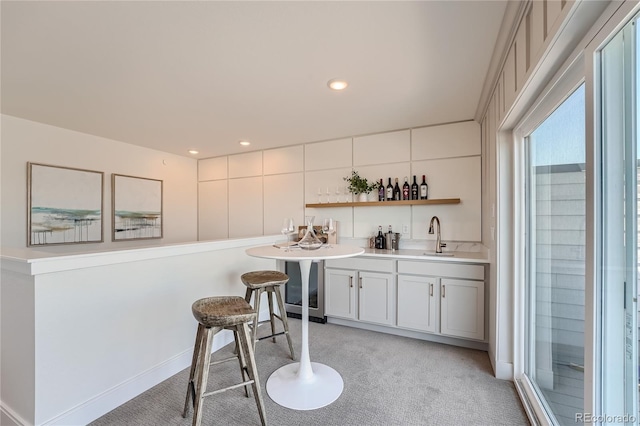 bar featuring indoor wet bar, recessed lighting, light colored carpet, a sink, and baseboards