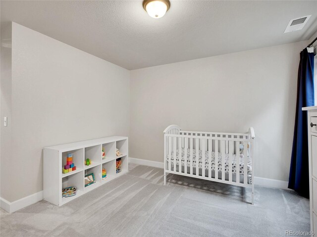 bedroom featuring light carpet, baseboards, and a textured ceiling
