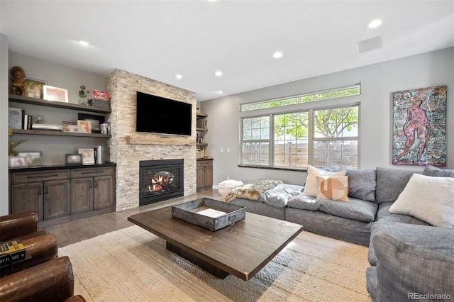 living room with a stone fireplace and light hardwood / wood-style floors