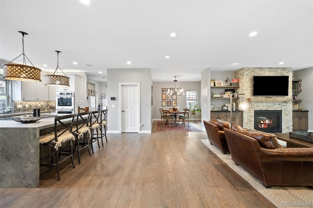 living room featuring a fireplace, light hardwood / wood-style flooring, and a notable chandelier