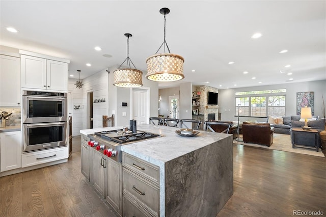 kitchen featuring white cabinetry, hanging light fixtures, a center island, and stainless steel appliances