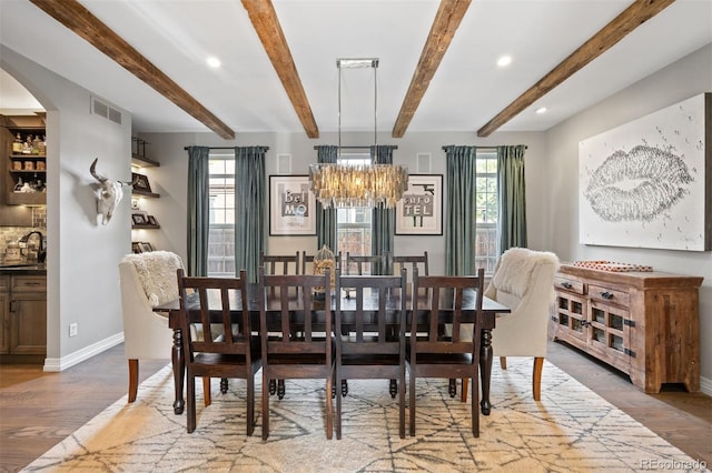 dining area featuring beamed ceiling, hardwood / wood-style flooring, plenty of natural light, and sink