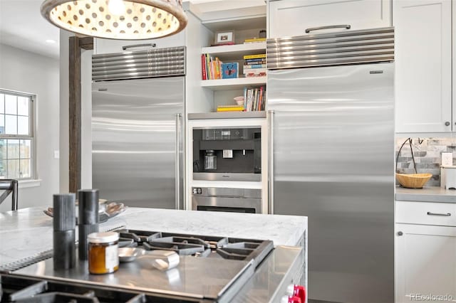 kitchen with white cabinets, stainless steel appliances, light stone counters, and tasteful backsplash