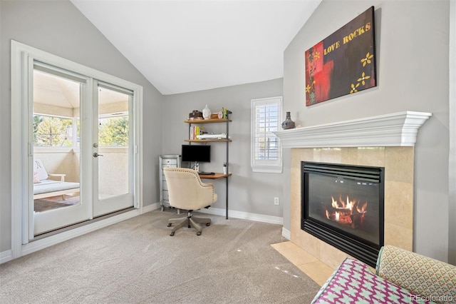 office area featuring a tiled fireplace, light carpet, french doors, and vaulted ceiling