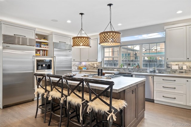 kitchen with appliances with stainless steel finishes, a breakfast bar, a kitchen island, pendant lighting, and white cabinetry