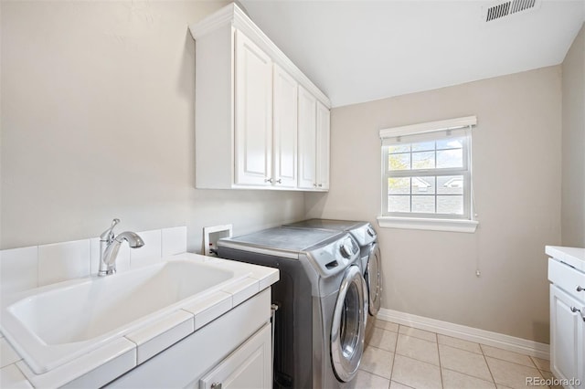 laundry area with washer and clothes dryer, light tile patterned flooring, cabinets, and sink