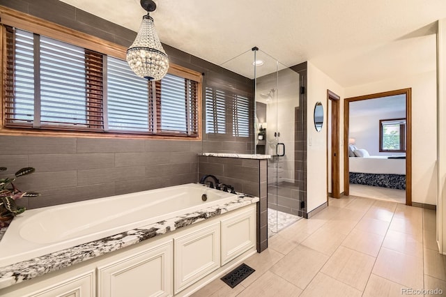 5475 W Ottawa Ave, Littleton, CO 80128 - ensuite bathroom with a garden tub, a shower stall, a chandelier, tile patterned floors, and baseboards
