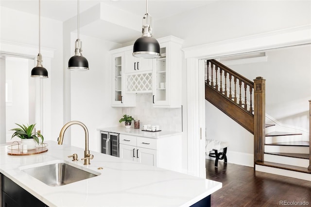 kitchen featuring white cabinetry, sink, hanging light fixtures, and light stone counters