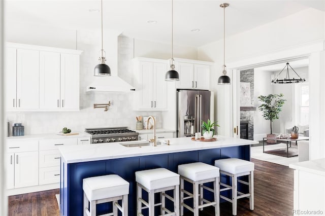 kitchen featuring white cabinets, an island with sink, high quality fridge, and sink