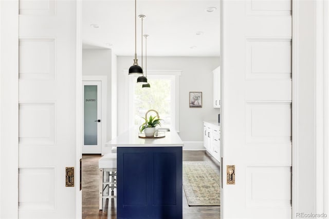 kitchen with white cabinetry, a center island, dark hardwood / wood-style floors, decorative light fixtures, and a breakfast bar area