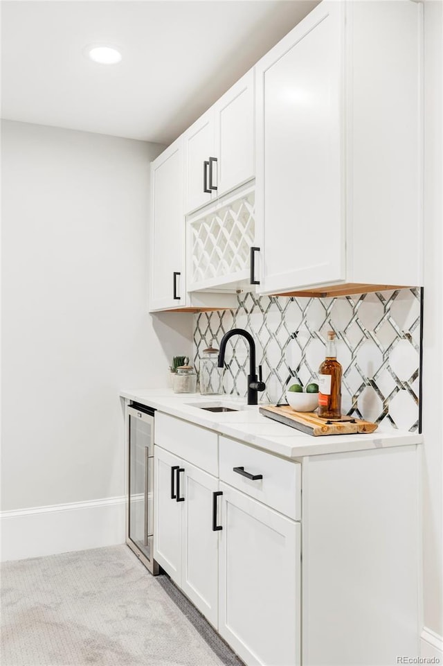 bar featuring white cabinets, tasteful backsplash, wine cooler, and sink