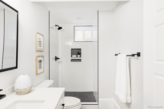 bathroom with tiled shower, vanity, and toilet